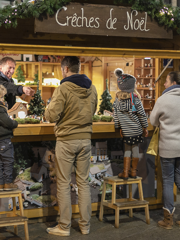 Couple avec deux enfants achetant une crèche de Noël sur le marché de Noël de Louvain-la-Neuve